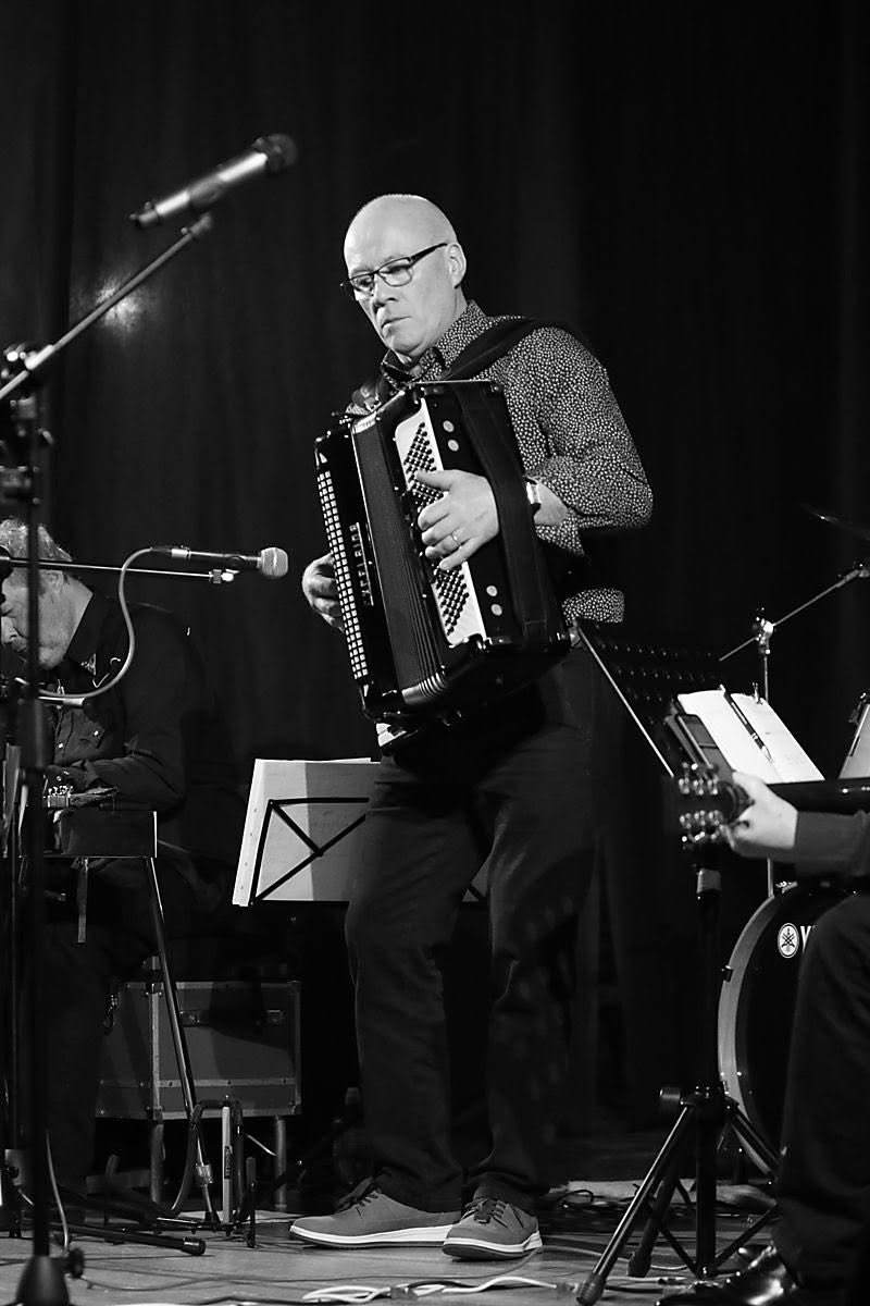 A musician playing the accordion on stage at a live music night in the Marian Hall