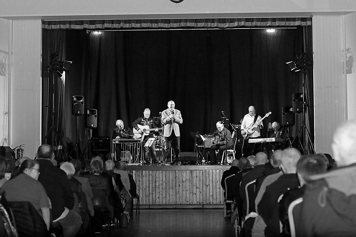 A band performing on stage in the Marian Hall to a full seated audience